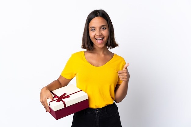 Young latin woman holding a gift isolated