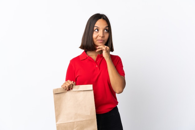 食料品の買い物袋を持っている若いラテン女性