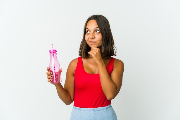 Young latin woman holding a milkshake relaxed thinking about something looking at a copy space.