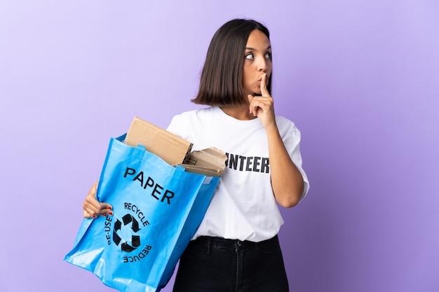 Young latin woman holding a recycling bag full of paper to recycle isolated