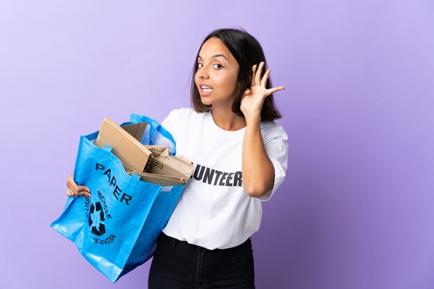 Young latin woman holding a recycling bag full of paper to recycle isolated