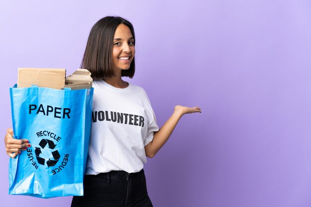 Young latin woman holding a recycling bag full of paper to recycle isolated