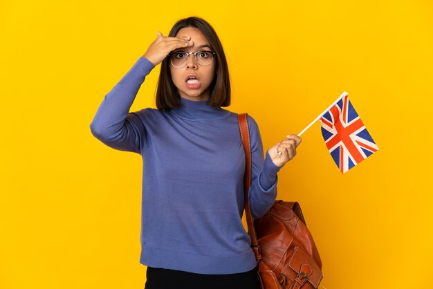 Young latin woman holding an United Kingdom flag isolated on yellow background has realized something and intending the solution