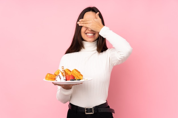 Young latin woman holding a waffles isolated