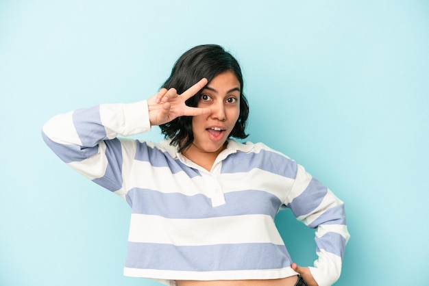 Young latin woman isolated on blue background dancing and having fun