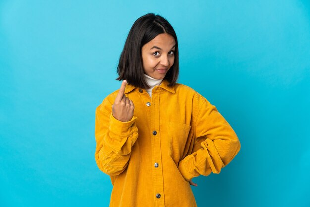 Young latin woman isolated on blue background doing coming gesture