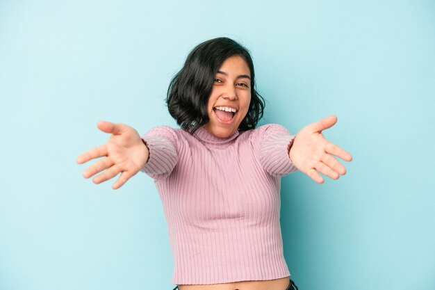 Young latin woman isolated on blue background feels confident giving a hug to the camera.