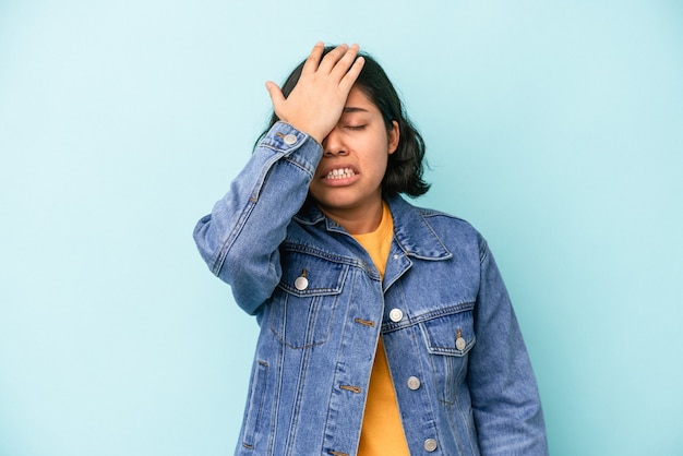 Foto giovane donna latina isolata su sfondo blu dimenticando qualcosa, schiaffeggiando la fronte con il palmo e chiudendo gli occhi.