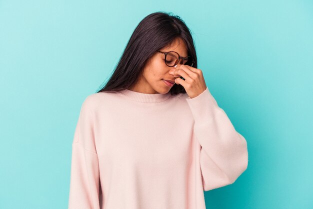 Young latin woman isolated on blue background having a head ache, touching front of the face.