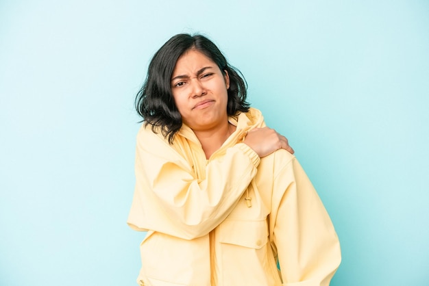 Young latin woman isolated on blue background having a shoulder pain.