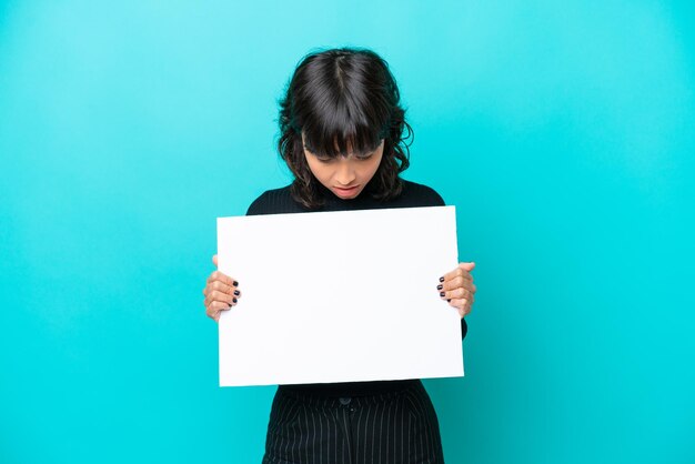 Young latin woman isolated on blue background holding an empty placard and looking it