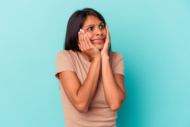 Young latin woman isolated on blue background scared and afraid.