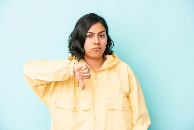 Young latin woman isolated on blue background showing thumb down, disappointment concept.