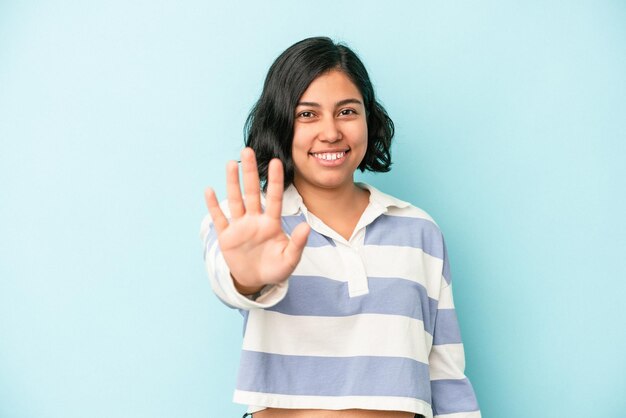 Young latin woman isolated on blue background smiling cheerful showing number five with fingers.