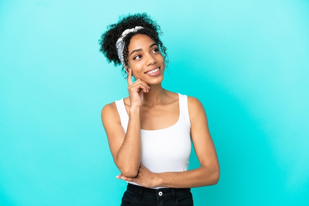 Photo young latin woman isolated on blue background thinking an idea while looking up