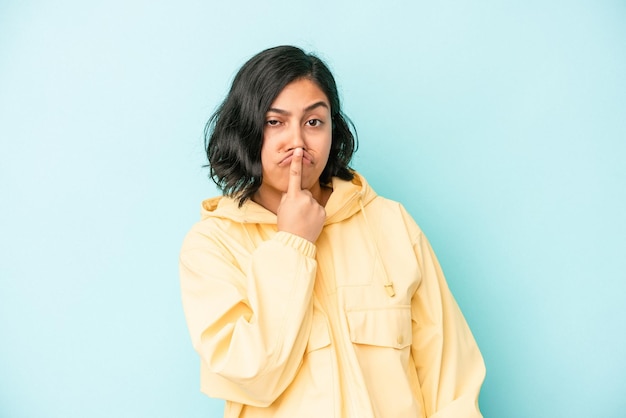 Young latin woman isolated on blue background thinking and looking up, being reflective, contemplating, having a fantasy.