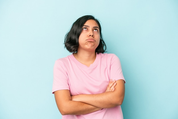 Young latin woman isolated on blue background tired of a repetitive task.