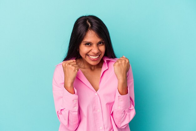 Young latin woman isolated on blue background upset screaming with tense hands.