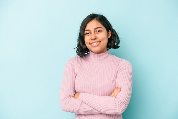 Young latin woman isolated on blue background who feels confident, crossing arms with determination.