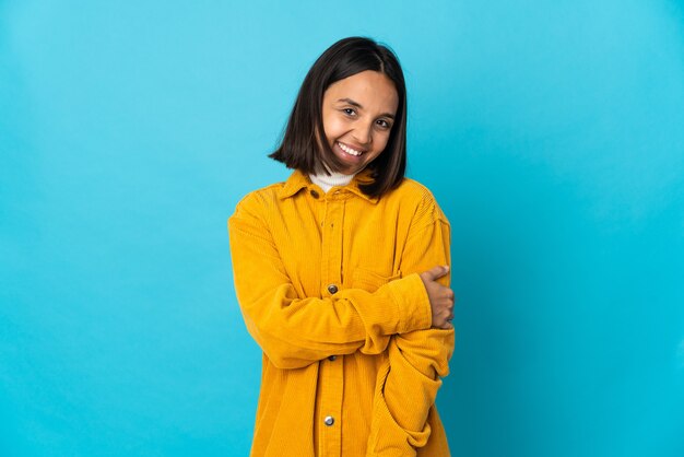 Young latin woman isolated on blue wall laughing