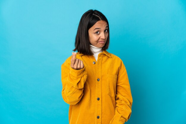 Young latin woman isolated on blue wall making money gesture