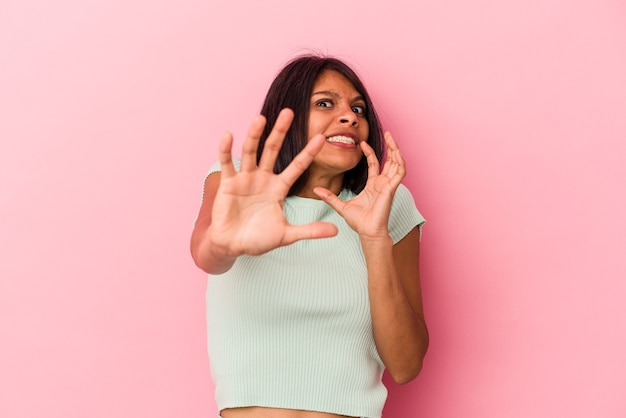 Foto giovane donna latina isolata su sfondo rosa scioccata a causa di un pericolo imminente