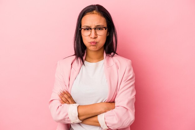 ピンクの背景に分離された若いラテン女性は頬を吹く疲れた表情顔の表情の概念