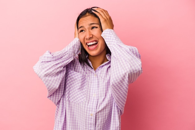 Young latin woman isolated on pink background  covering ears with hands trying not to hear too loud sound.