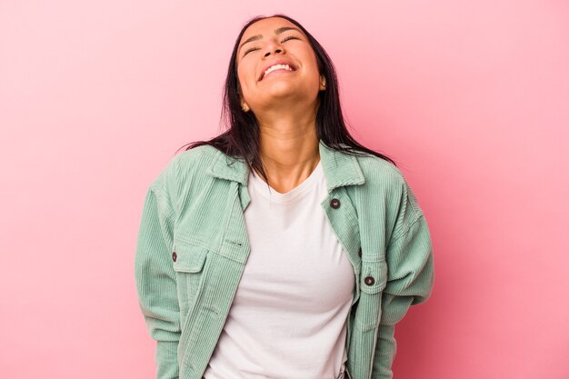 Young latin woman isolated on pink background  laughs and closes eyes, feels relaxed and happy.