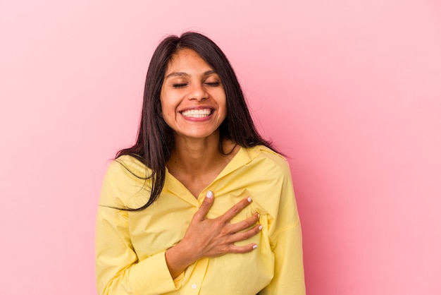 Young latin woman isolated on pink background laughs out loudly keeping hand on chest.