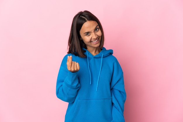 Young latin woman isolated on pink background making money gesture