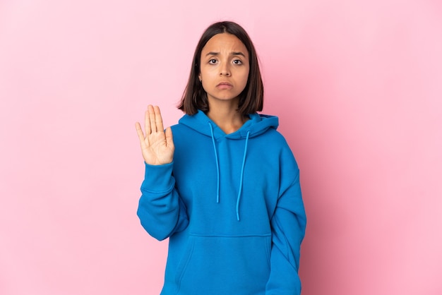 Young latin woman isolated on pink background making stop gesture