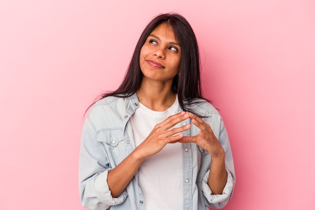 Foto giovane donna latina isolata su sfondo rosa che compone un piano in mente, creando un'idea.