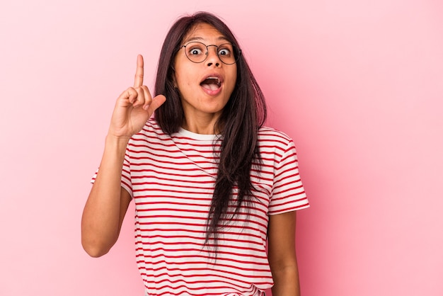 Young latin woman isolated on pink background pointing upside with opened mouth.