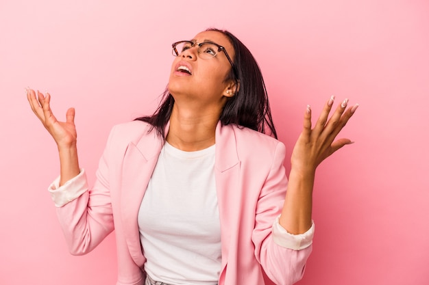 Young latin woman isolated on pink background  screaming to the sky, looking up, frustrated.