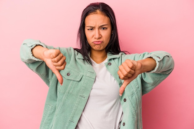 Young latin woman isolated on pink background  showing thumb down and expressing dislike