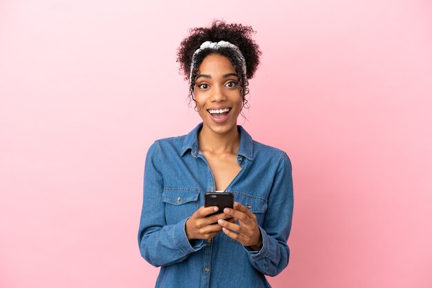 Young latin woman isolated on pink background surprised and sending a message