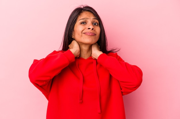 Young latin woman isolated on pink background touching back of head, thinking and making a choice.