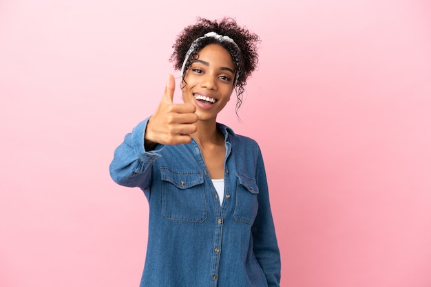 Young latin woman isolated on pink background with thumbs up because something good has happened