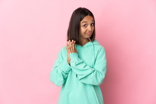 Young latin woman isolated on pink wall scheming something