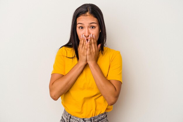 Young latin woman isolated on white background covering mouth\
with hands looking worried