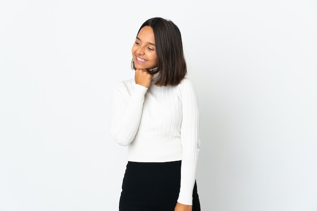 Young latin woman isolated on white background looking up while smiling