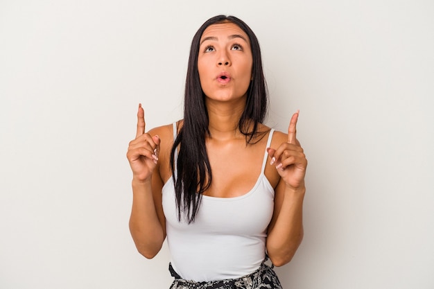 Young latin woman isolated on white background  pointing upside with opened mouth.