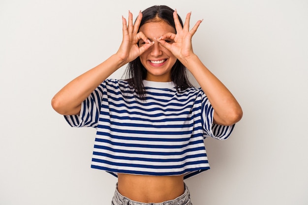 Young latin woman isolated on white background  showing okay sign over eyes