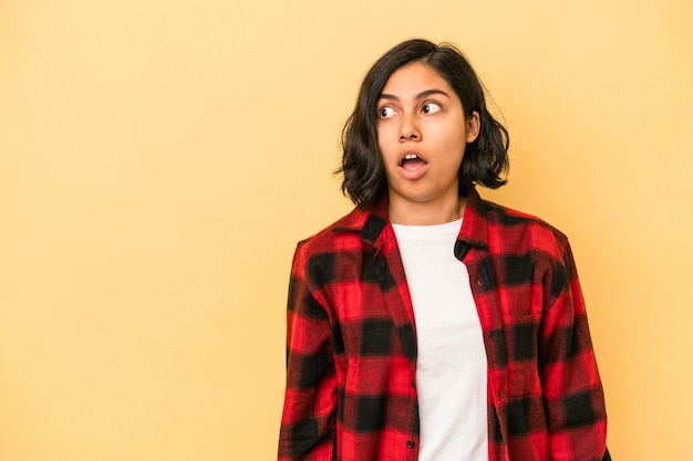 Young latin woman isolated on yellow background being shocked because of something she has seen.