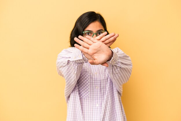 Young latin woman isolated on yellow background doing a denial gesture