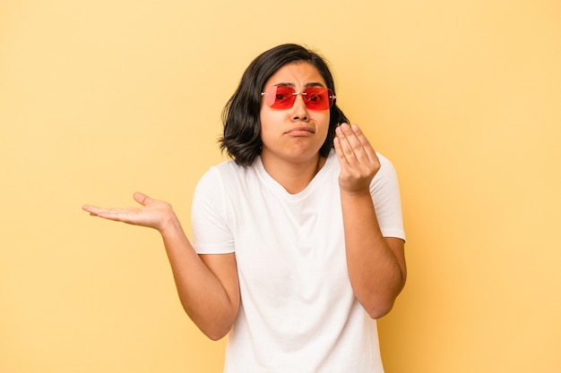 Young latin woman isolated on yellow background showing that she has no money.