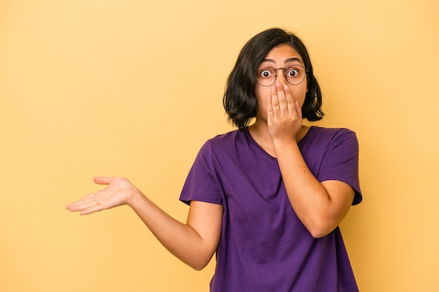 Young latin woman isolated on yellow background smiling cheerfully pointing with forefinger away.