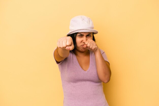 Foto giovane donna latina isolata su sfondo giallo che lancia un pugno, rabbia, combattimento a causa di una discussione, boxe.