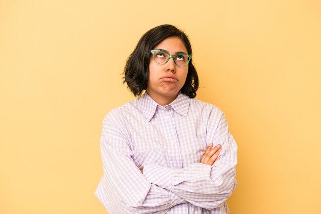 Young latin woman isolated on yellow background tired of a repetitive task.